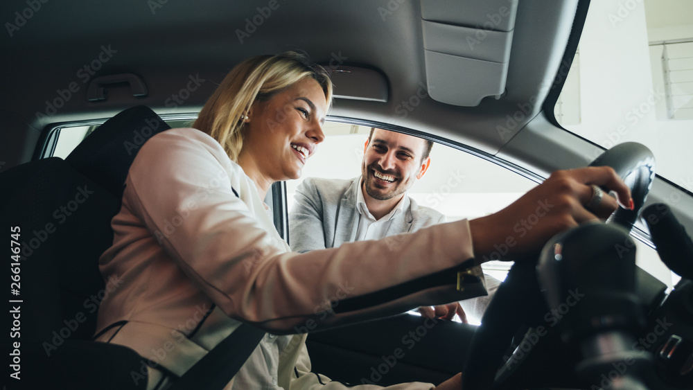 Woman buying a car in dealership sitting in her new auto