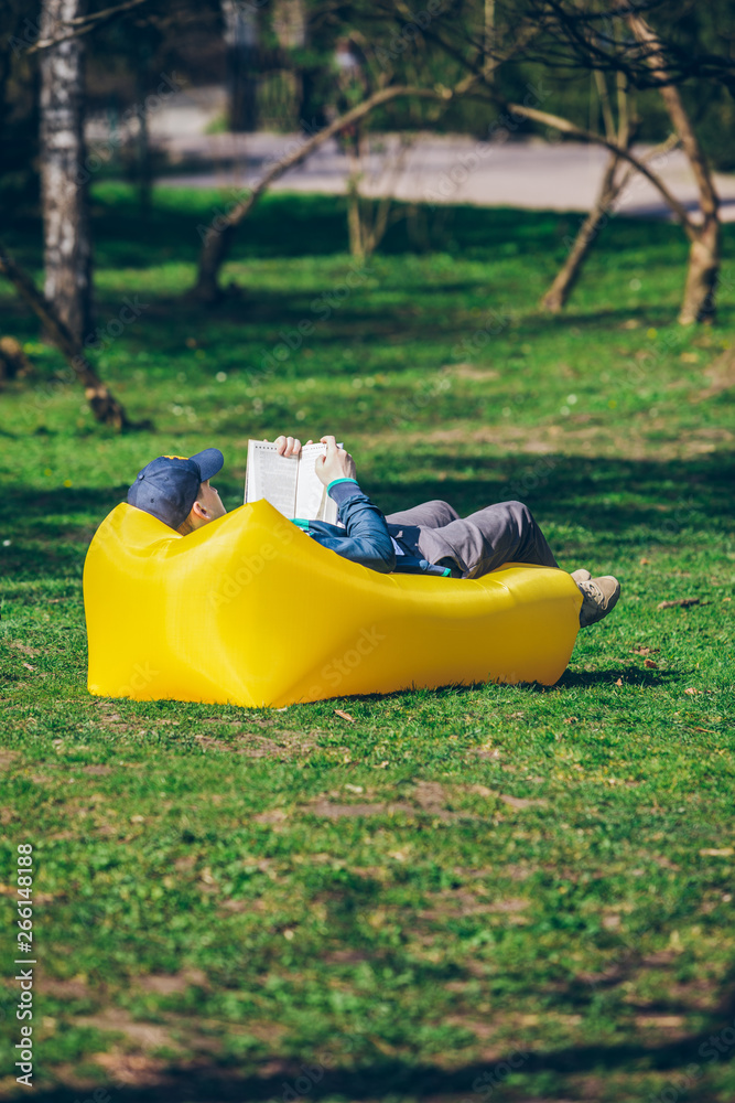 book reading concept. man in city park on inflatable mattress