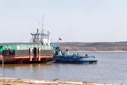 The movement of the ferry through the deep Urals River in Russia in the sunny spring afternoon. Working crossing.