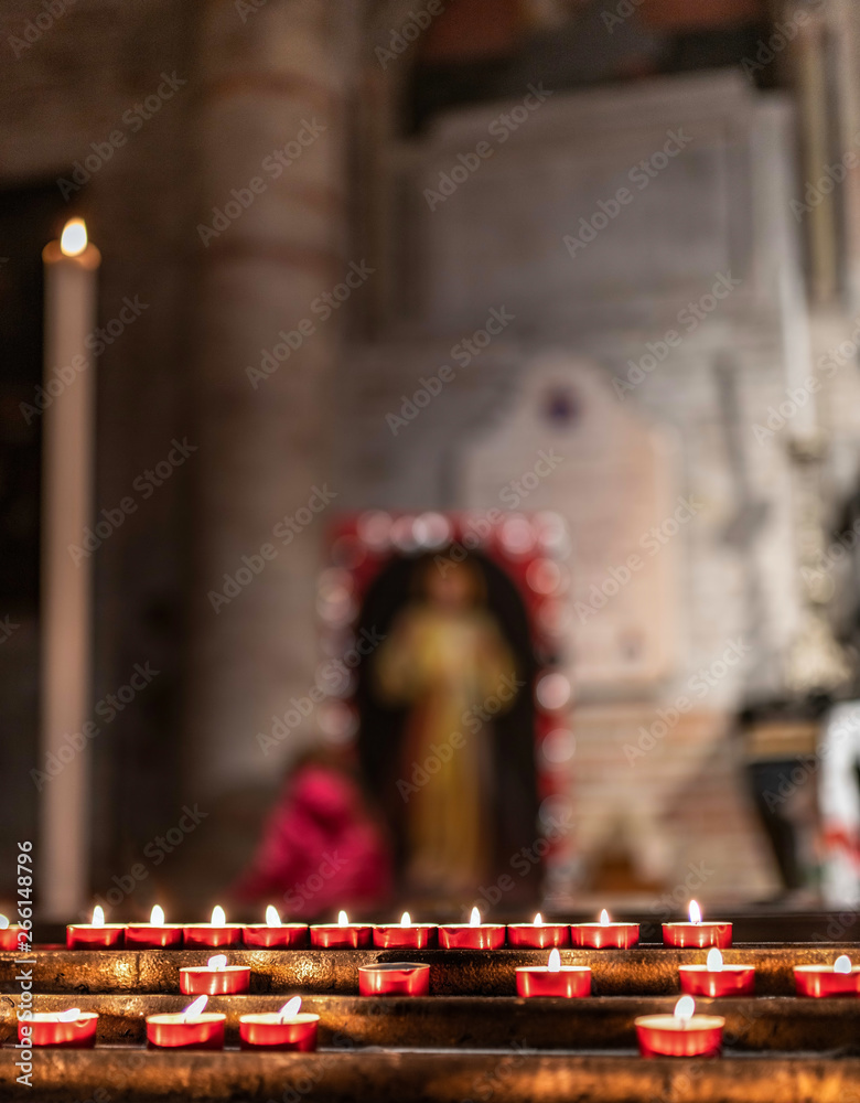 Candele e lumini di devozione e preghiera dei fedeli sullo sfondo di un  altare sacro di una chiesa, con immagini sacre e di santi in preghiera  Stock Photo | Adobe Stock