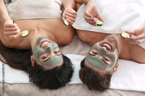 Happy couple enjoying facial treatment procedure in spa salon, above view