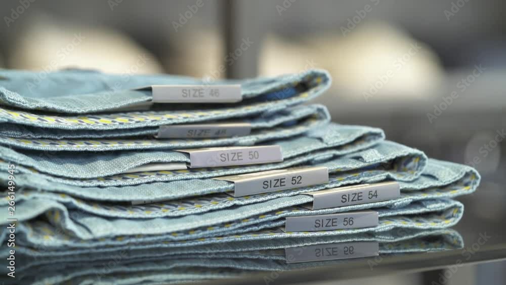 A close-up of shop assistant placing blue male trousers onto a shelf in a clothing shop. Fashion boutique routine work A close-up of shop assistant placing blue male trousers onto a shelf in a clothing shop. Fashion boutique routine work