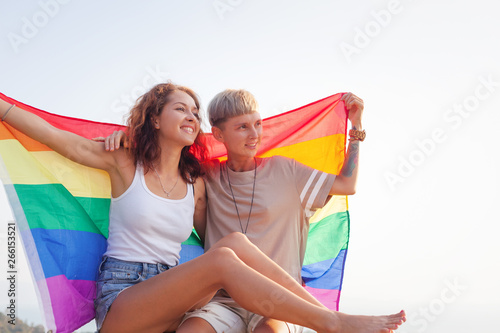 Beautiful lesbian couple with rainbow flag. Romantic relationship. Gender equality, family lifestyle. © olezzo