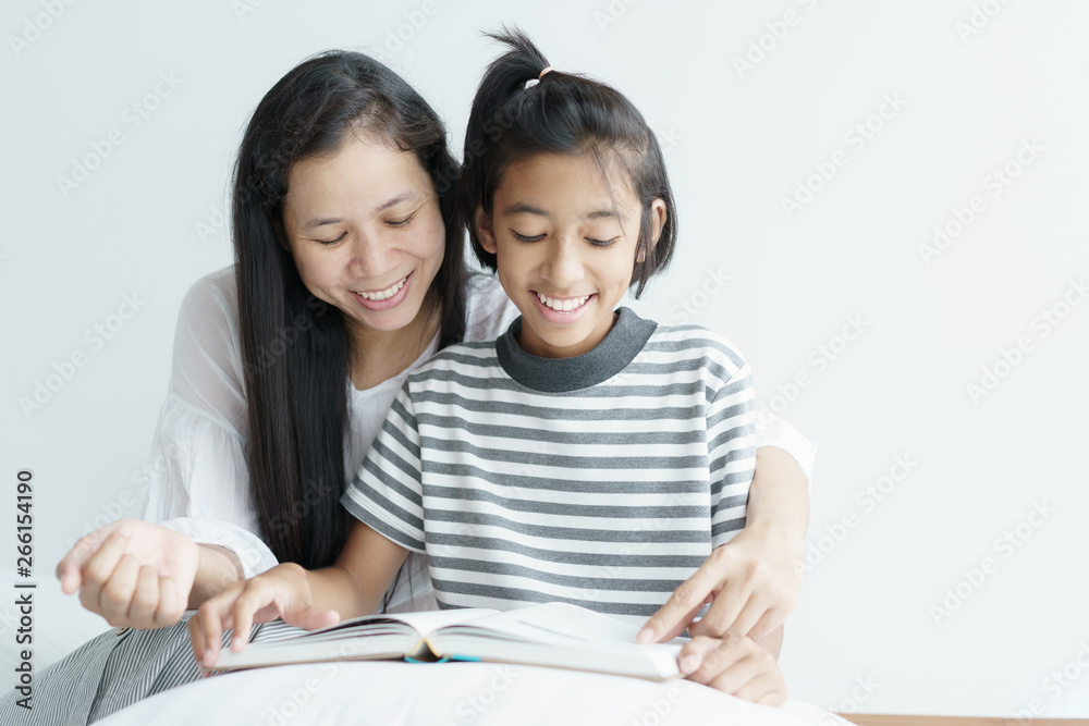 Portrait picture of love family mother and daughter sitting reading books . Cute girl smile beautiful and happy on bed. Portrait picture of love family mother and daughter sitting reading books . Cute girl smile beautiful and happy on bed.