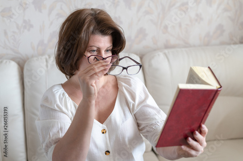 Woman with impaired vision reading a book through two glasses photo