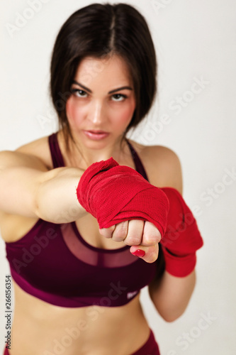 beautiful woman boxer with red strap on wrist. Fitness girl preparing for boxing training on gray background © producer