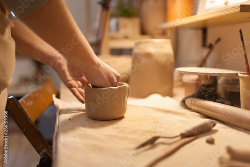 Female potter works with ceramic at his workshop. Young woman work inside 