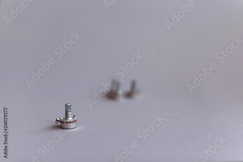 Potentiometers stand on the gray background. Many Potentiometers. Macro close up of electronic component potentiometer
