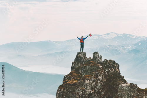 Man on mountain summit adventure climbing extreme active lifestyle vacations outdoor in Norway success raised hands emotions
