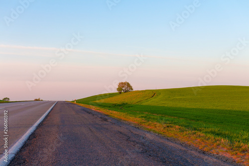 sunrise dawn over a rural meadow field and country driving road. Countryside landscape sun over horizon dawn behind the city copy space