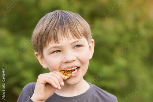 Boy trying to taste the Bitcoin in the summer in the Park