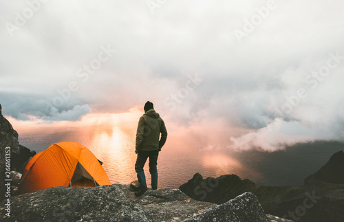 Man traveling with tent camping on mountain top outdoor adventure lifestyle  hiking active extreme summer vacations sunset and clouds view