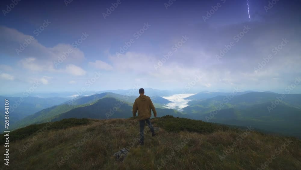 The male walking on the mountain against the lightning background