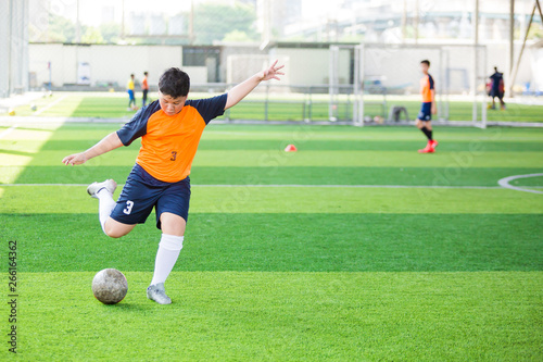 Soccer player speed run to shoot ball to goal on artificial turf.