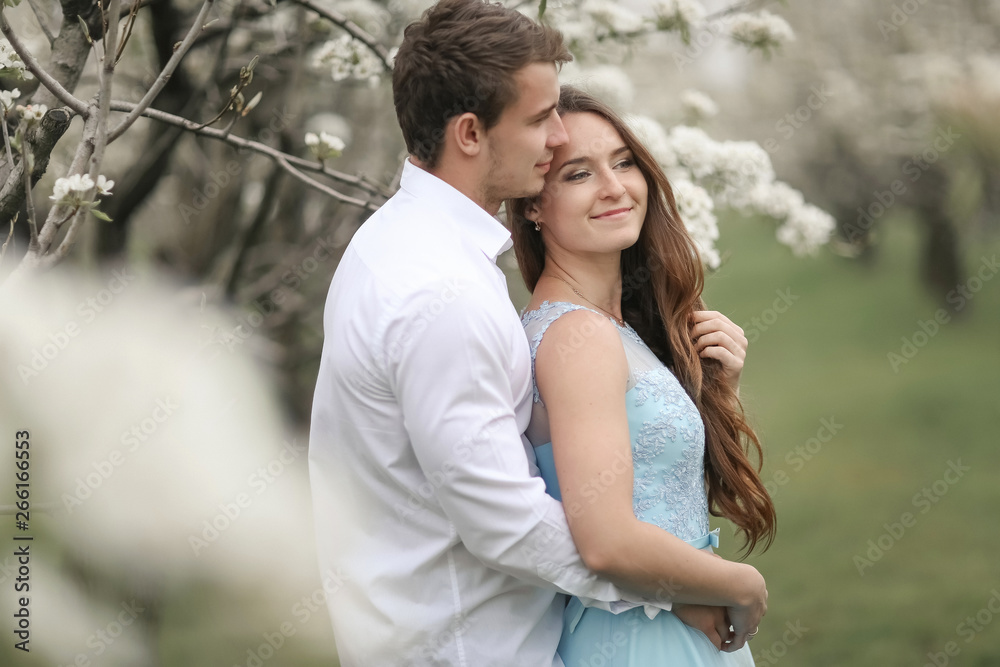 A Kissing newlywed couple spending time in blooming garden. A Kissing newlywed couple spending time in blooming garden.