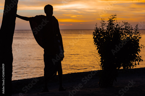 Masai man looking at sunset over the sea at Kizimkazi in Unguja aka Zanzibar Island Tanzania East Africa photo