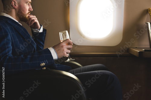 Fotografie A young successful businessman in an expensive suit sits in the chair of a priva