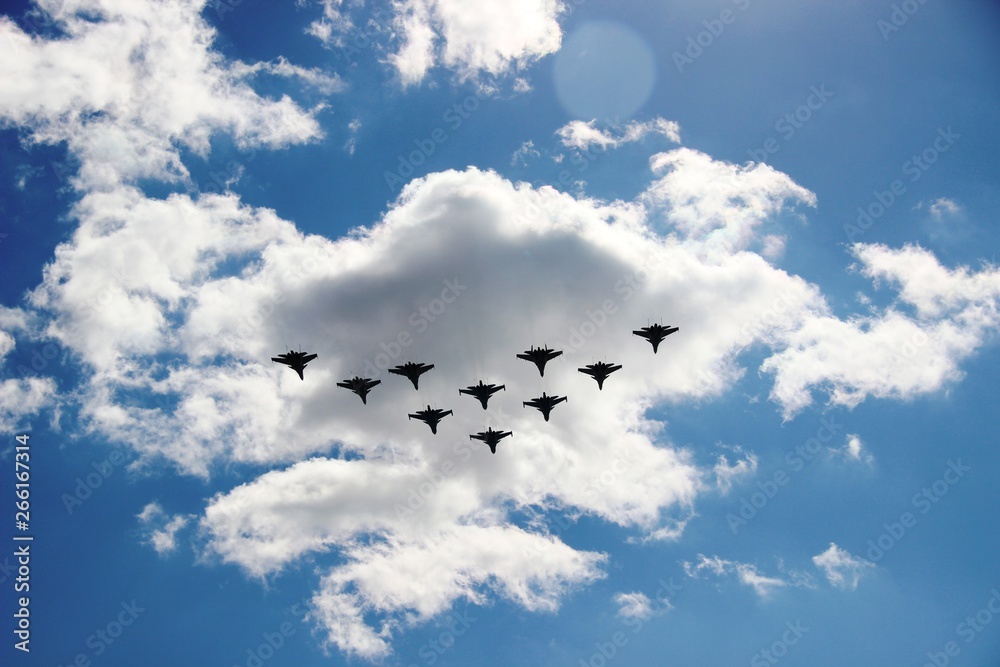 A group of ten aircraft in a blue sky with white clouds. Ten planes in a blue sky with clouds on a Sunny day, selective focus A group of ten aircraft in a blue sky with white clouds. Ten planes in a blue sky with clouds on a Sunny day, selective focus