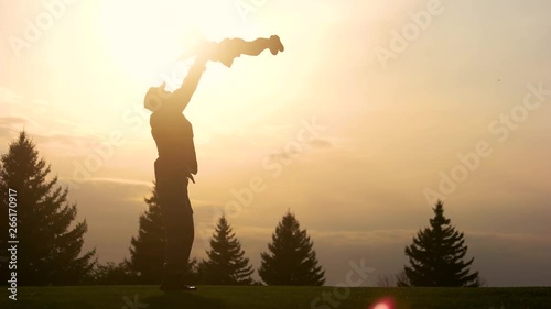 Father having fun with daughter silhouette. Father lifting up his daughter in the park while sunset.