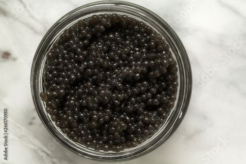 Jar with delicious black caviar on grey background. Top view