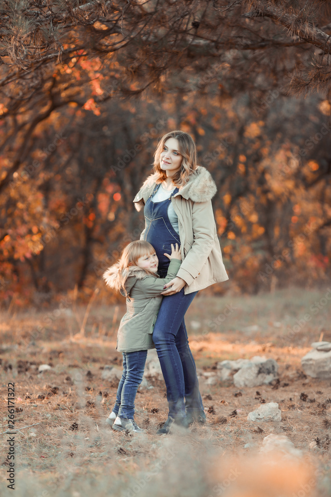 Fototapeta premium A pregnat Mother hugging her child during walk in the park