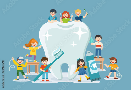 Group of smiling boys and girls standing next to big white tooth holding toothbrush showing healthy clean tooth encouraging teeth hygiene and care.