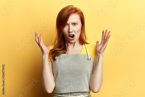 frustrated girl in apron expresses her negative emotions. close up photo. feeling, frutration, waitress scolding clients, young female garderner shouting at somebody, woman photo