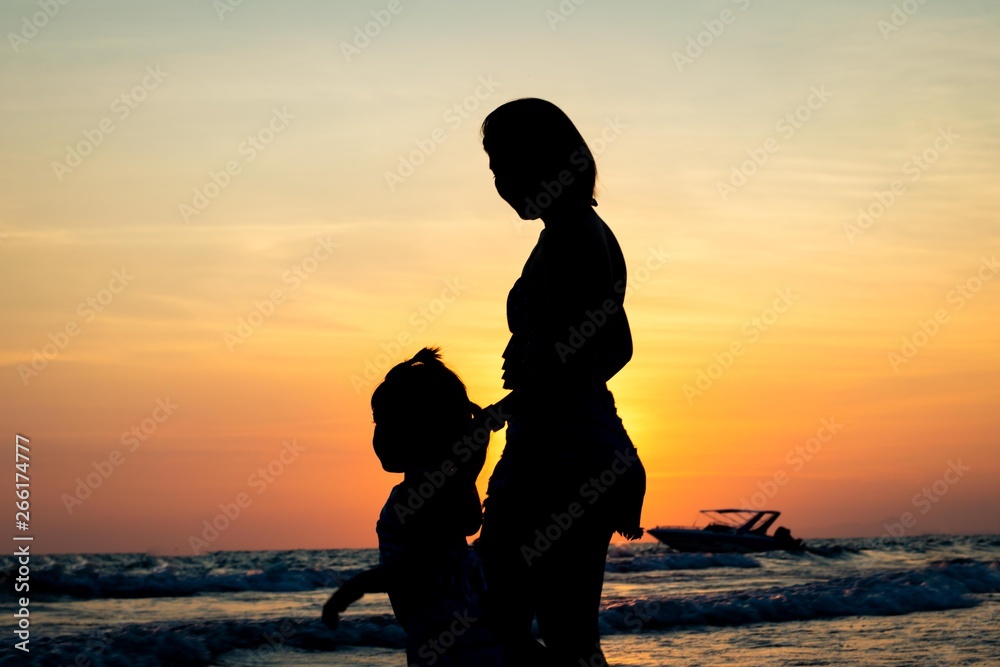 silhouette of lovely mother and her baby on sunset beach