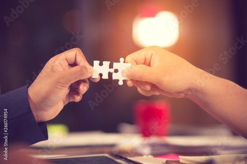 two hands of businessman to connect couple puzzle piece with sky background.Jigsaw alone wooden puzzle against sun rays.one part of whole.symbol of association and connection.business strategy