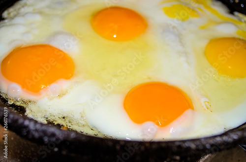 Appetizing fried five eggs cook in an old vintage cast iron skillet