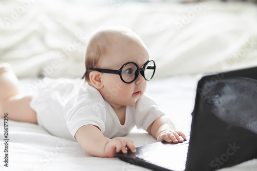 Foto A newborn baby is lying on a soft bed in glasses.