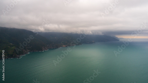 View over the Monterosso al Mare coast line and the Ligurian Sea turquoise water, from the Punta Mesco peak, on a rainy day with low clouds, in Cinque Terre, Italy.
