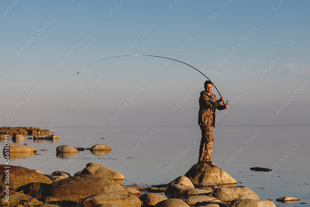 The fisherman checks the line, prepares and throws the bait far into the peaceful water. The fisherman checks the line, prepares and throws the bait far into the peaceful water.