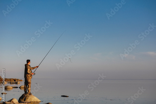 Fisherman catches a fish. Hands of a fisherman with a spinning rod reel