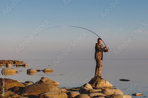 The fisherman checks the line, prepares and throws the bait far into the peaceful water.