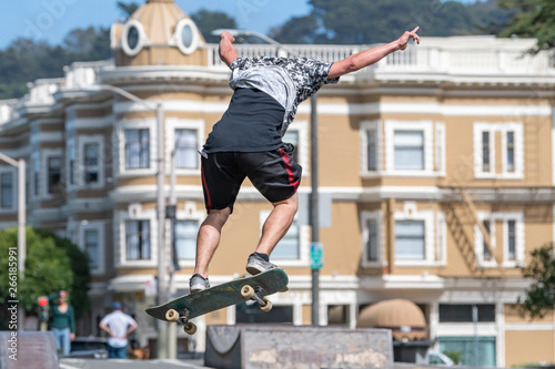 A skate boarder flies off the ramp at the Stanyan Skatepark in San Francisco near the end of Haight Street. Victorian buildings in the background. Sunny day.