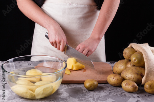 young woman in an apron cuts potatoes