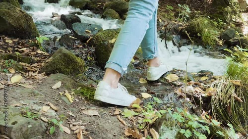  footpath covered with green juicy grass, tream of cold, Female legs close-up feet walking on stones, gravel, river bank, nature mountain water. Happy woman walking  enjoy nature. Borjomi Georgia photo