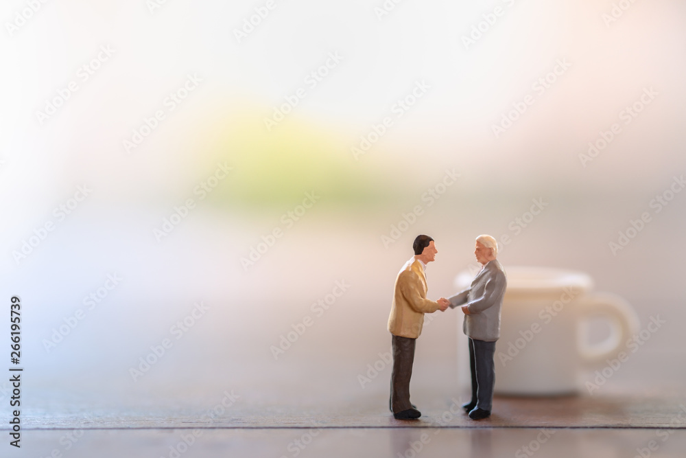 Coffee, Time and Business cooperation concept. Two businessman miniature figures meet and hand shake on wooden table with mini cup of hot coffee as background. Coffee, Time and Business cooperation concept. Two businessman miniature figures meet and hand shake on wooden table with mini cup of hot coffee as background.