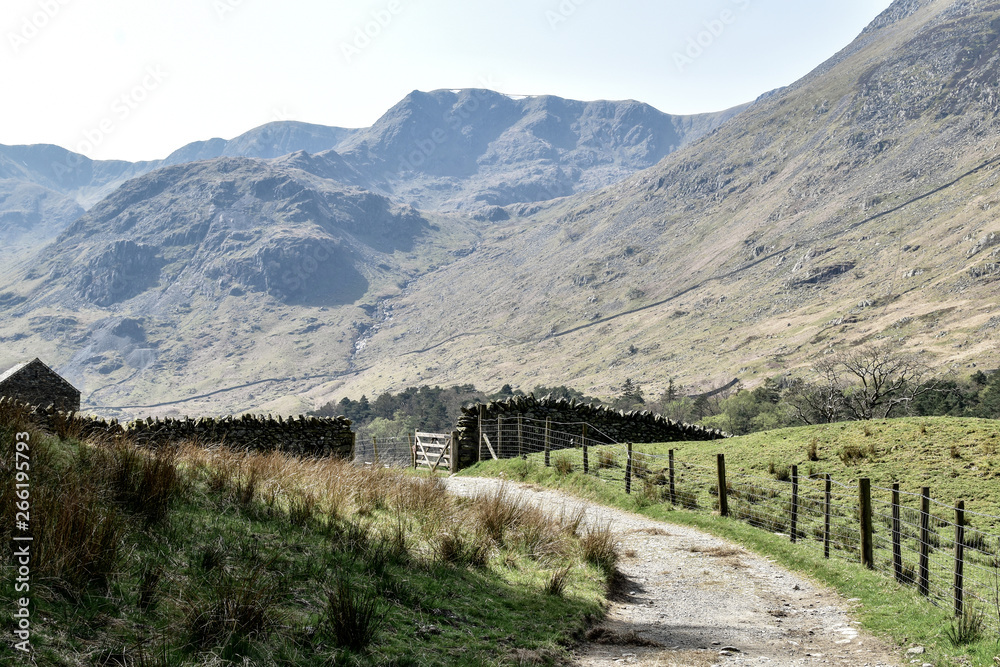 Gravel path leading up to stone wall with wooden gate. Stunning nature in the background. Slightly toned down colors. Grisedale pike, Lake District, England, UK -Image