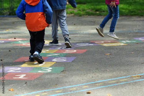 Closeup of kids feet jumping and playing hopscotch in school yard