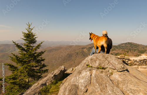 Person sitting on a rock with they dog.  