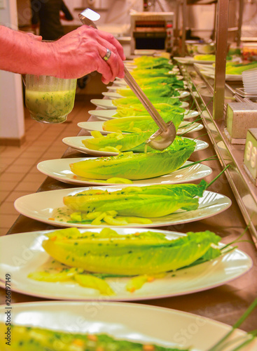 Chef adding dressing to a salad.  