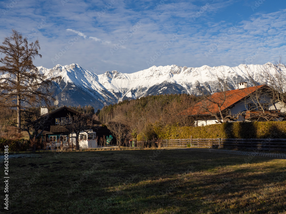 Paisaje Austriaco con campo, casas y al fondo montañas nevadas por la zona de Igls en Innsbruck, invierno de 2018