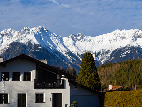 Paisaje Austriaco con campo, casas y al fondo montañas nevadas por la zona de Igls en Innsbruck, invierno de 2018