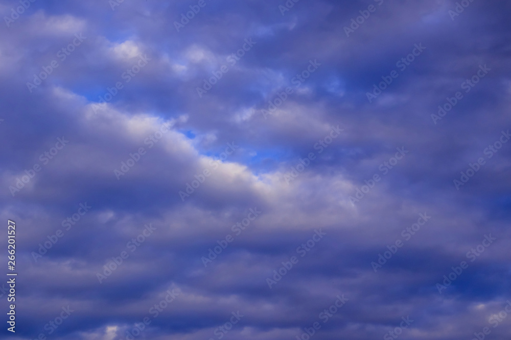 The sky in the clouds with the light of the sunset. The texture of the clouds, the background image.