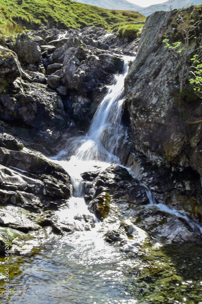 Stream leading out to small waterfall. Slow shutter speed. Bright sunny day. Grisedale pike, Lake District, England, UK Stream leading out to small waterfall. Slow shutter speed. Bright sunny day. Grisedale pike, Lake District, England, UK