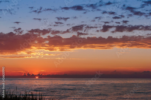 Sunset over the sea. Reflection of sunlight in the sea waves. The sky in the sunset rays.