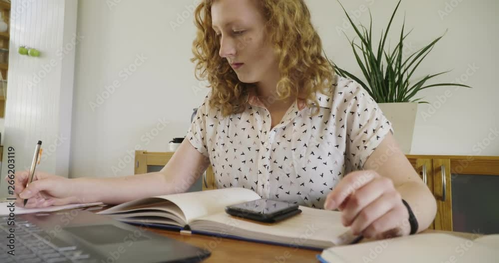 Young studen, blonde woman studying and working behind laptop, with books and notepad Young studen, blonde woman studying and working behind laptop, with books and notepad
