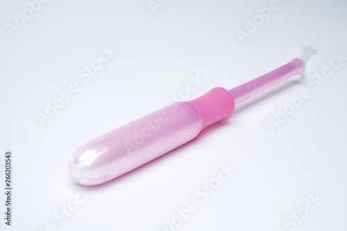 Pink protect, hygienic tampon in applicator close up on white background.